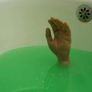No photo editing was used on this photo. Ghost has effectively filled his own bathtub with water and added some green coloring to the water. How did he pull off the trick with the hand? Well, Ghost had a friend and made a bet with that friend that he wouldn't dare to lie down in a bath full of green water and stay under water for a full two minutes...Of course that's not true. Ghost doesn't reveal how he managed to do this, (just like magicians, photographers never reveal their tricks) except that all his friends, ex-girlfriends and relatives still have both hands.