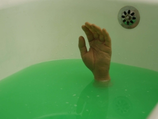 No photo editing was used on this photo. Ghost has effectively filled his own bathtub with water and added some green coloring to the water. How did he pull off the trick with the hand? Well, Ghost had a friend and made a bet with that friend that he wouldn't dare to lie down in a bath full of green water and stay under water for a full two minutes...Of course that's not true. Ghost doesn't reveal how he managed to do this, (just like magicians, photographers never reveal their tricks) except that all his friends, ex-girlfriends and relatives still have both hands.